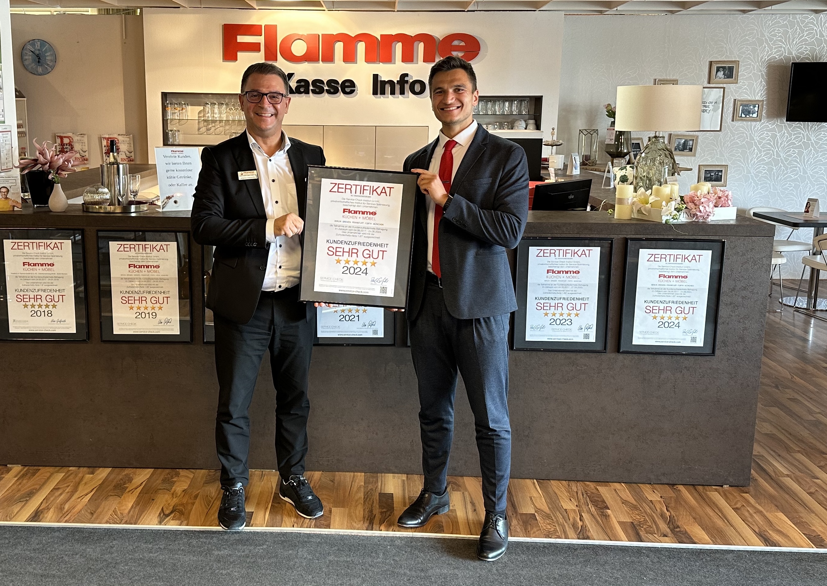 Feierliche Auszeichnung von Flamme Küchen + Möbel mit dem Service-Check Siegel 2024  (Personen von l.n.r.: Lampros Diamantis - Hausleiter am Standort München, Pablo C. Gräfrath - Institut SERVICE-CHECK)